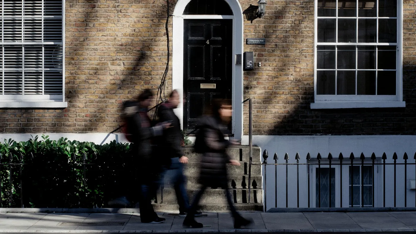 People walking past a Georgian brick office building with a black front door in London